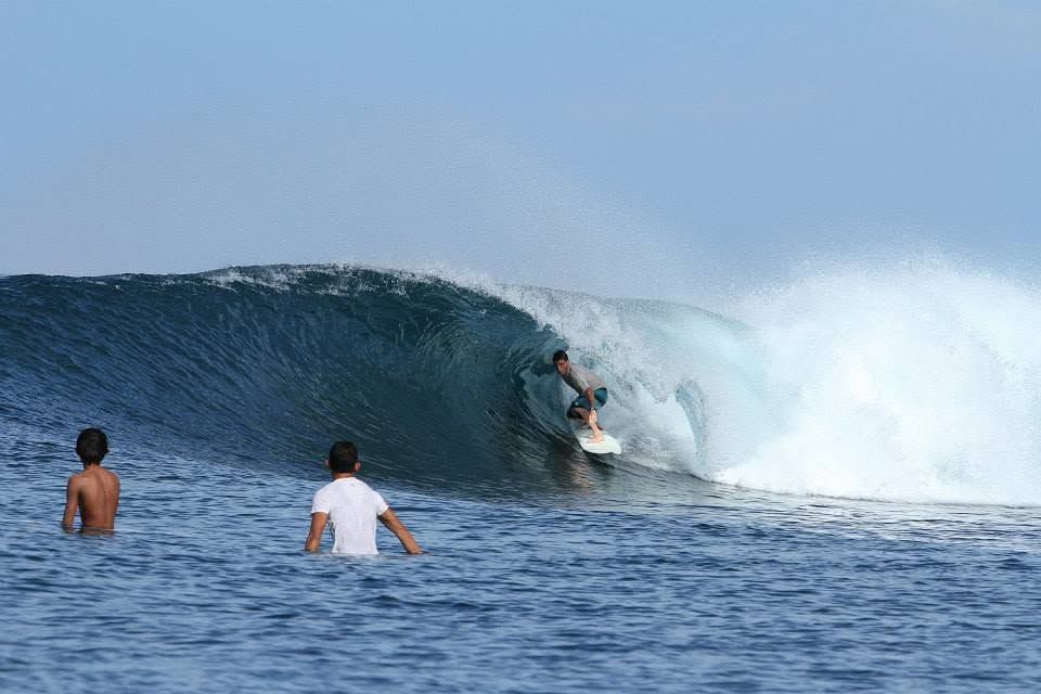 Kevin riding a blue barrel as two people watch from the water