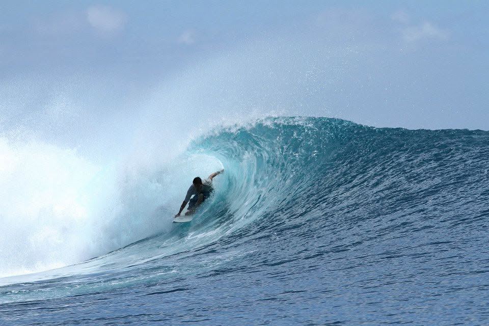 Kevin deep inside a glassy blue barrel
