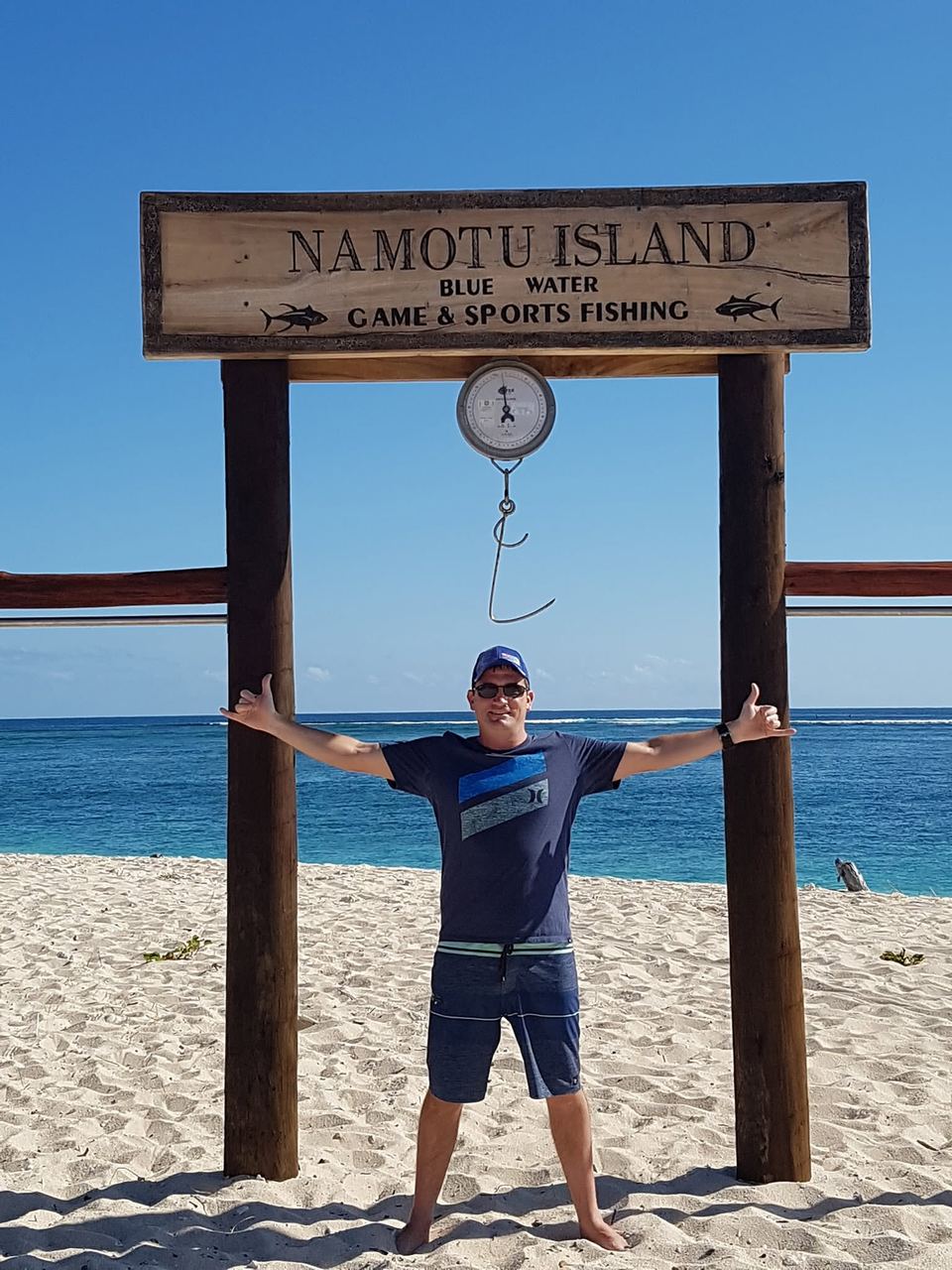 Kevin with his arms outstretched under the Namotu Island sign in Fiji